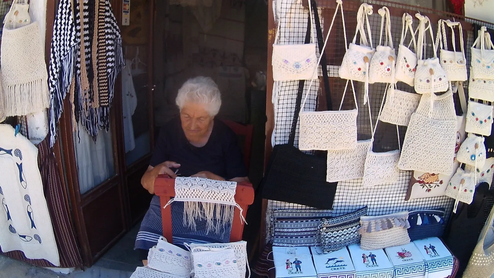 A village weaver working at her loom among hanging handmade textiles