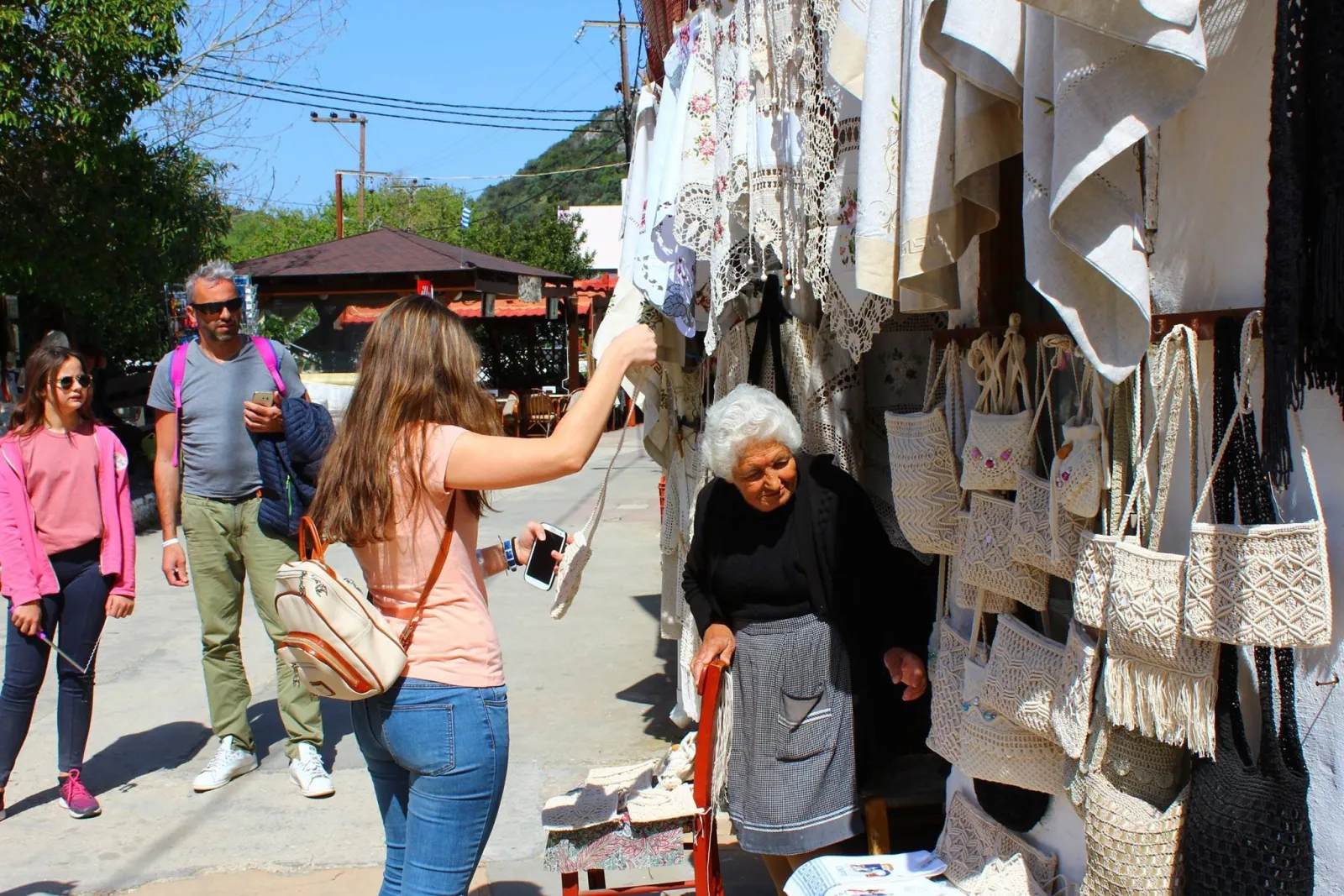 Visitors browsing woven bags and textiles at a village shop