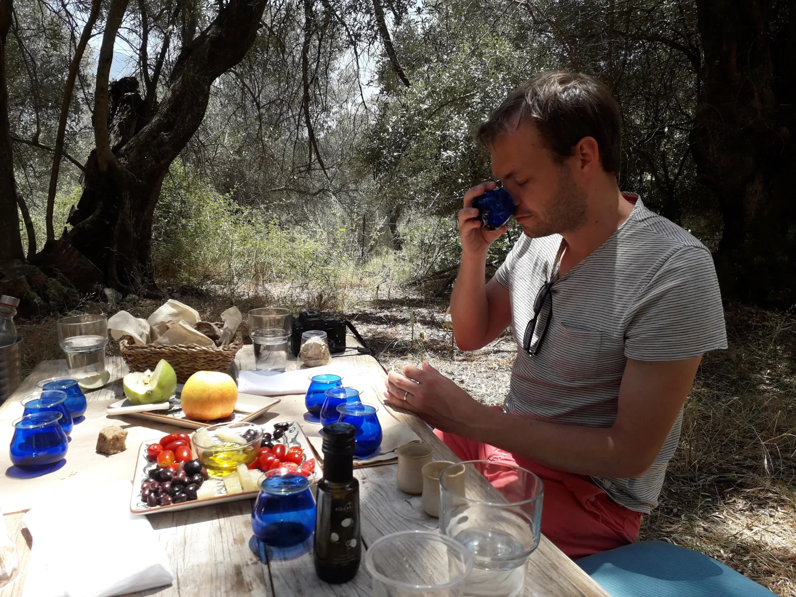 A guest nosing olive oil from a blue tasting glass at the table