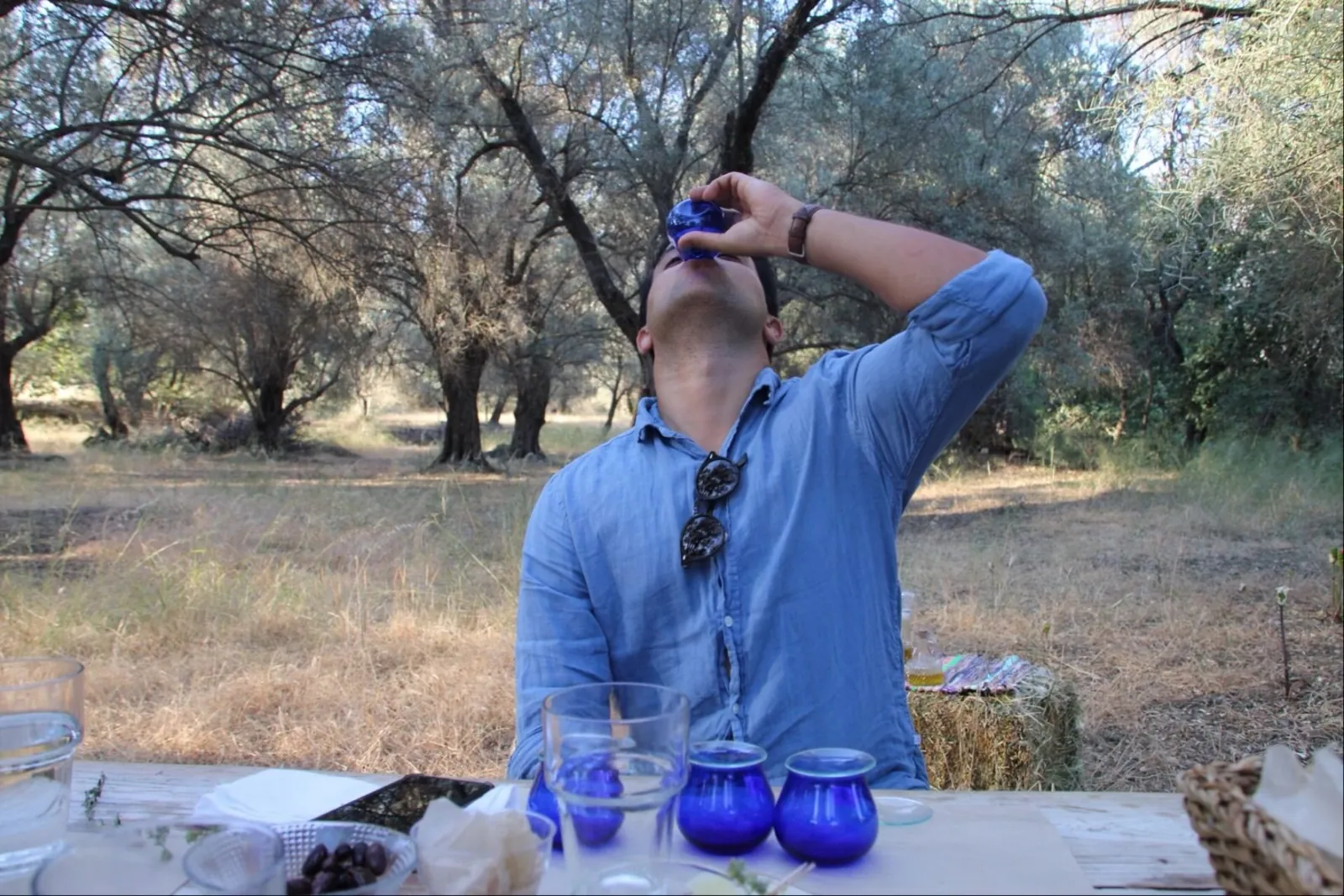 A guest drinking olive oil from a blue tasting glass