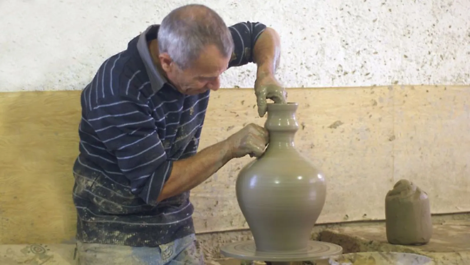 The potter throwing a jug on the wheel at the village studio