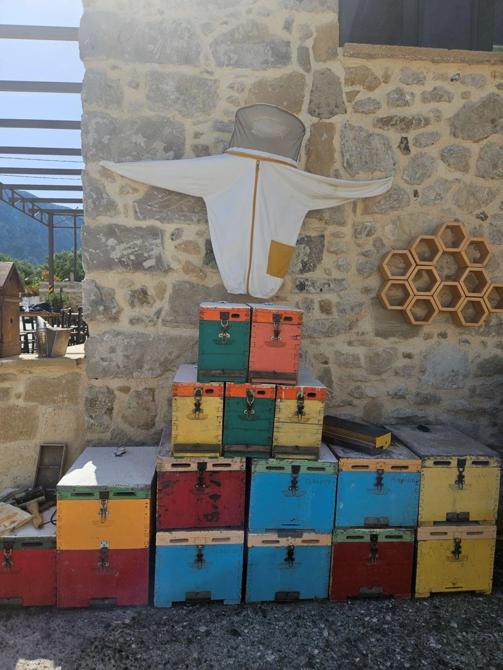 Brightly painted beehives stacked against a stone wall