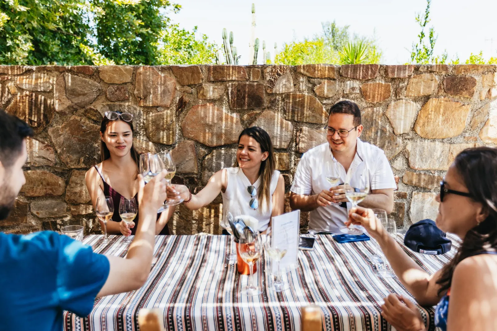 Guests tasting wine at a long table in a walled courtyard